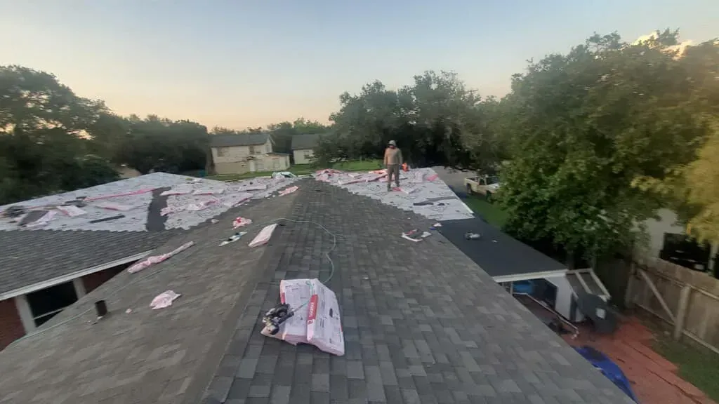 A man is standing on the roof of a house.