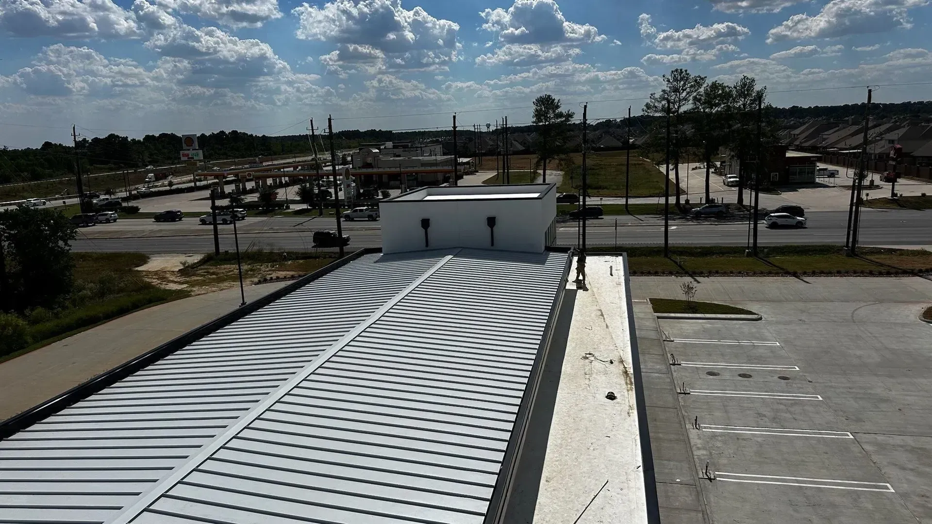 An aerial view of a roof with a parking lot in the background