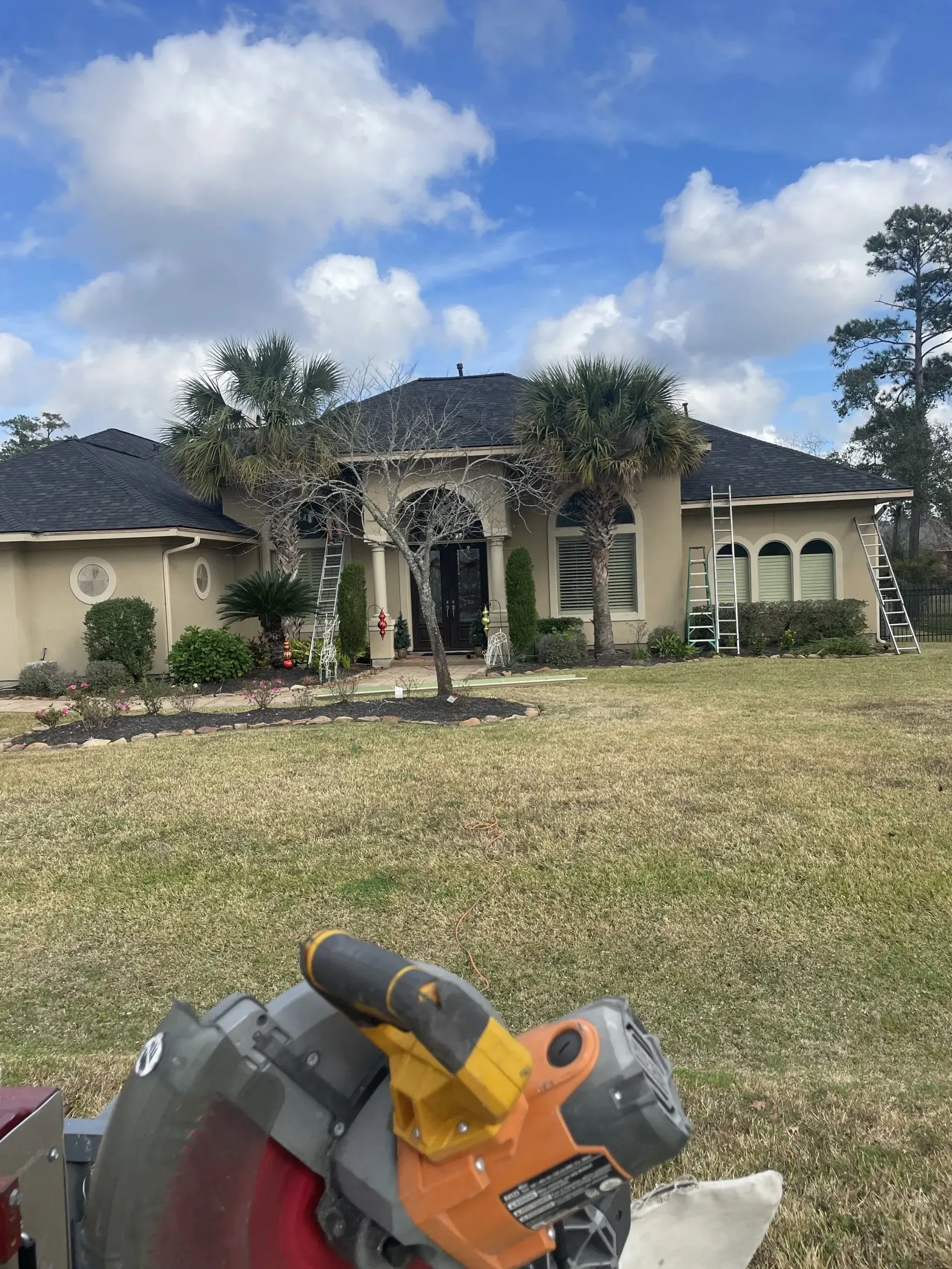 A circular saw is sitting in front of a large house.