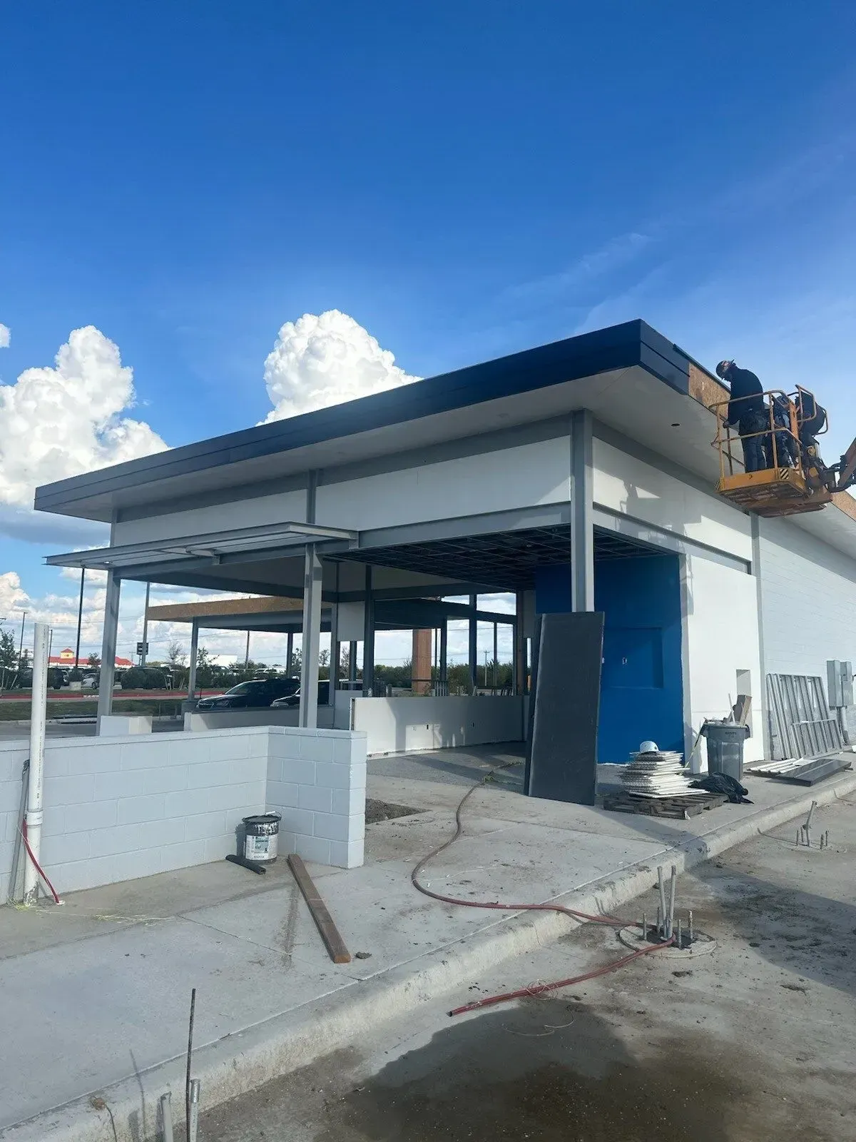 A white building with a blue door is under construction.