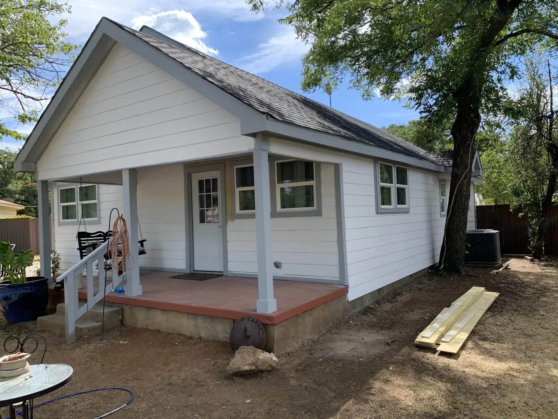 A small white house with a porch and a table in front of it