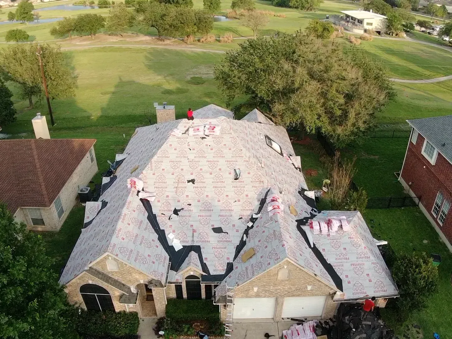An aerial view of a house being remodeled with a golf course in the background.
