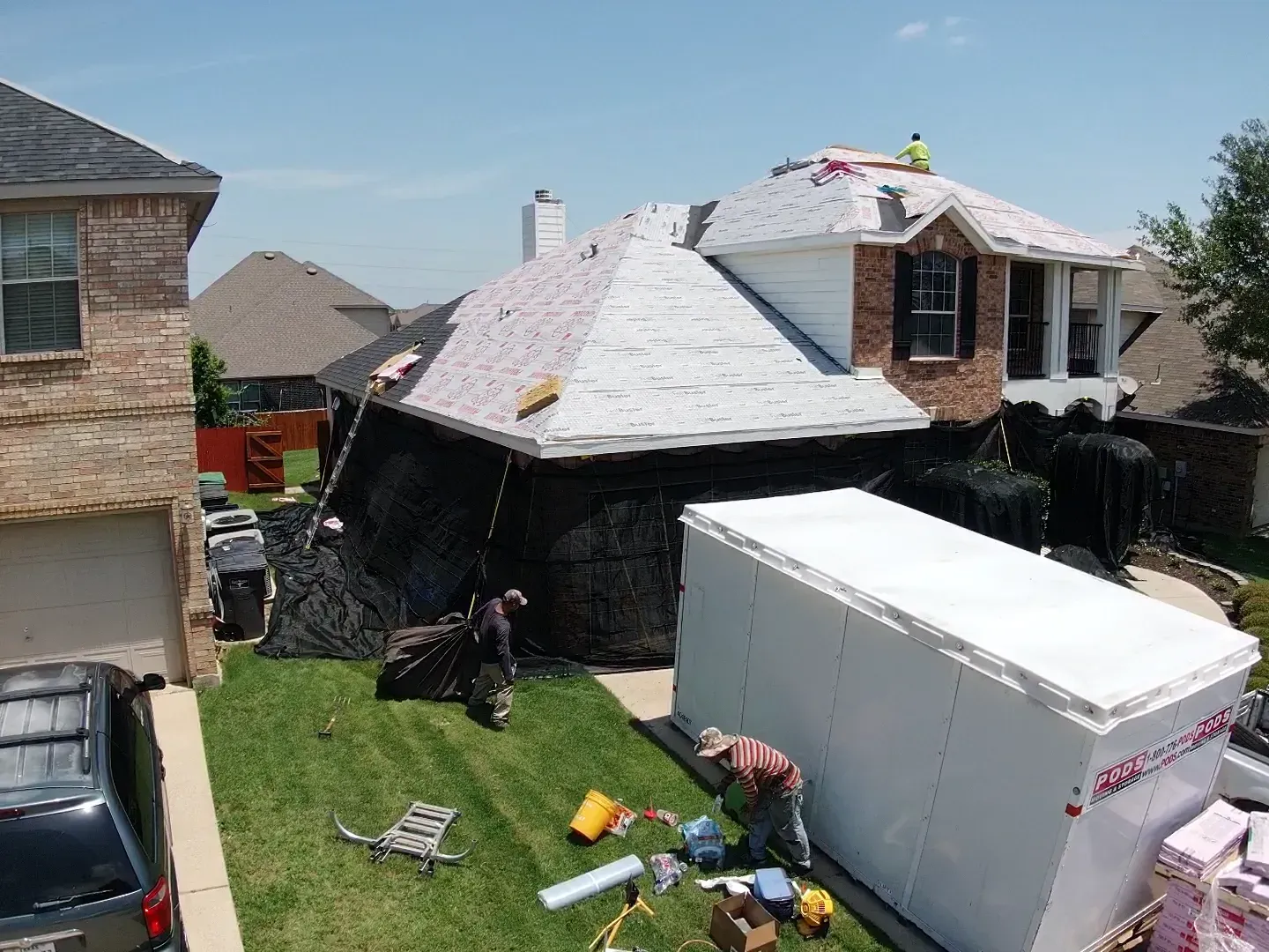 A white trailer is parked in front of a house being remodeled