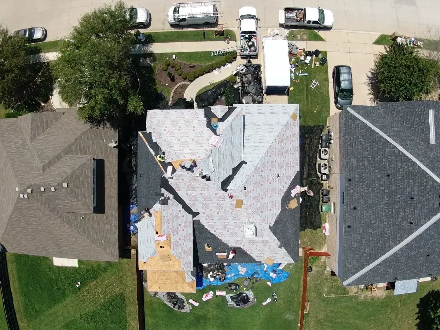 An aerial view of a house under construction with a roof being installed.