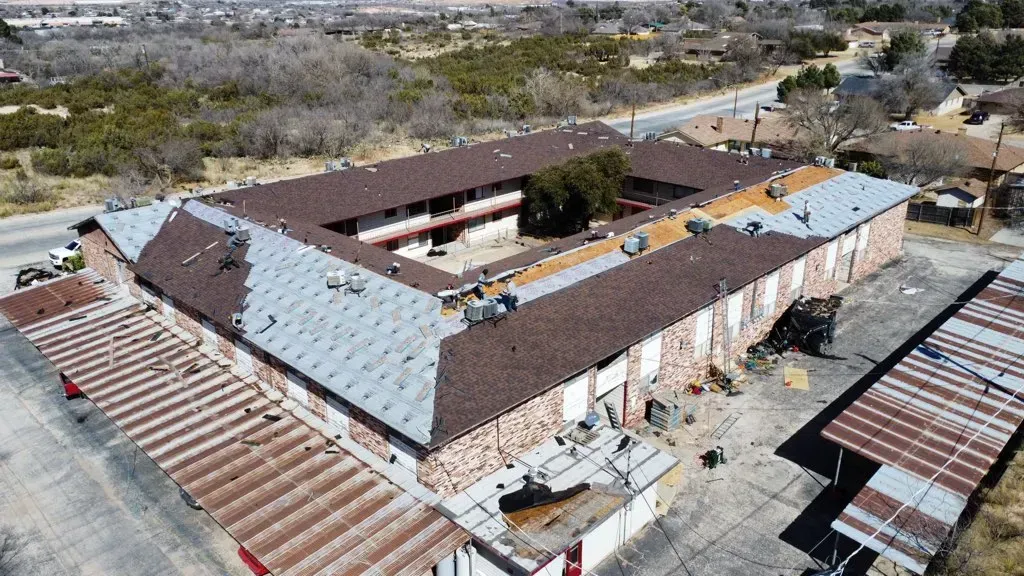An aerial view of a large building with a roof that is being repaired.