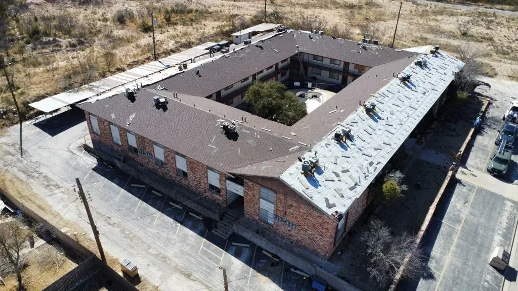 An aerial view of a large brick building with a brown roof.
