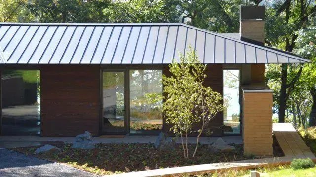 A small house with a black roof and a chimney
