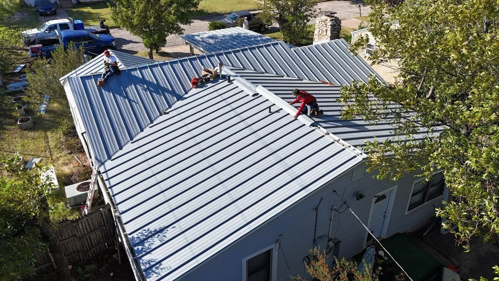 An aerial view of a house with a metal roof being installed.