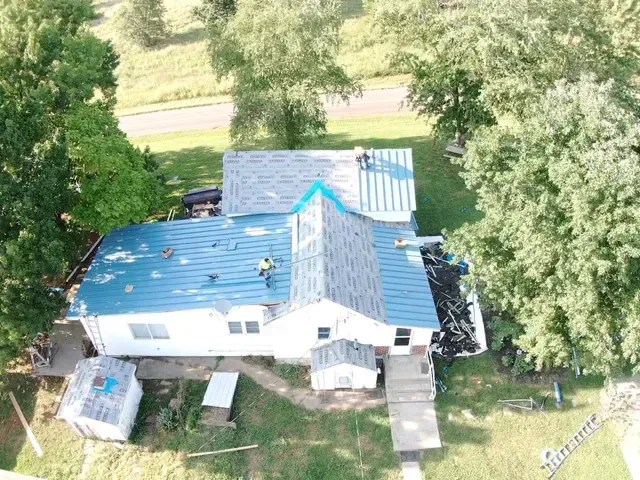An aerial view of a house with a blue roof being installed.