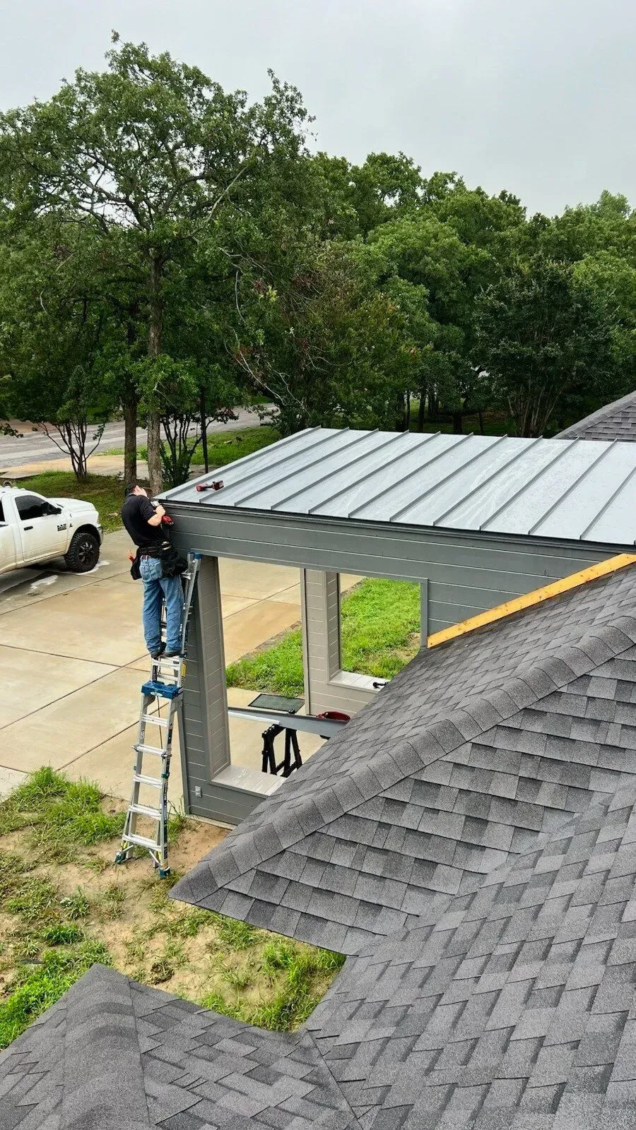 A man is standing on a ladder on top of a roof.