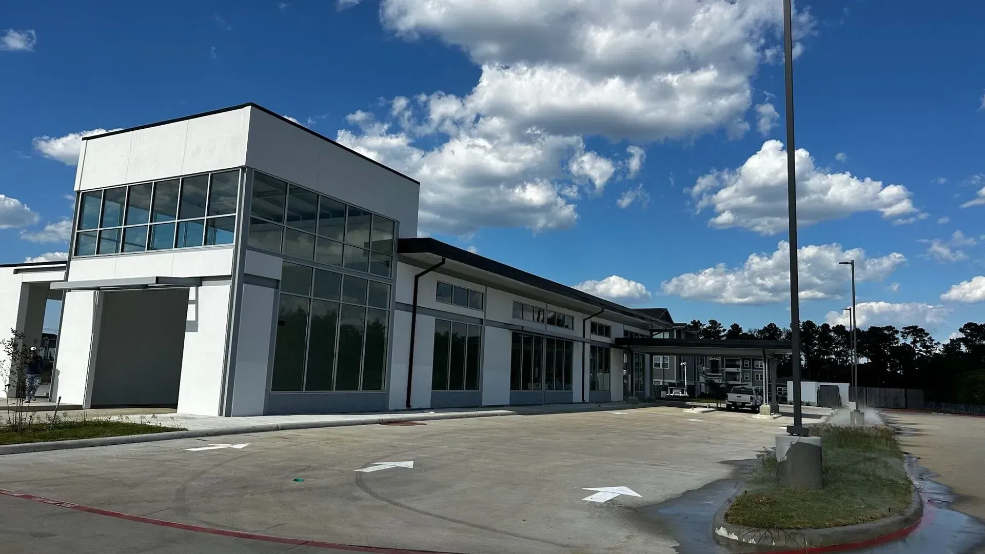 A large white building with a lot of windows is in a parking lot.