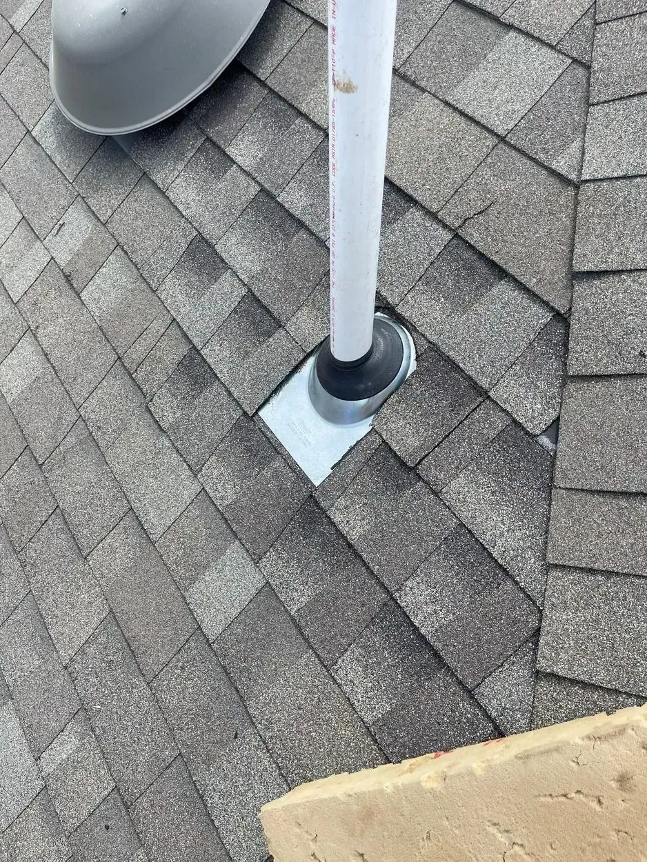 A white pipe is sitting on top of a brick roof.
