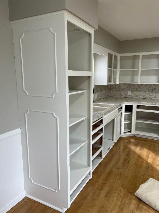 A kitchen with a lot of white cabinets and shelves