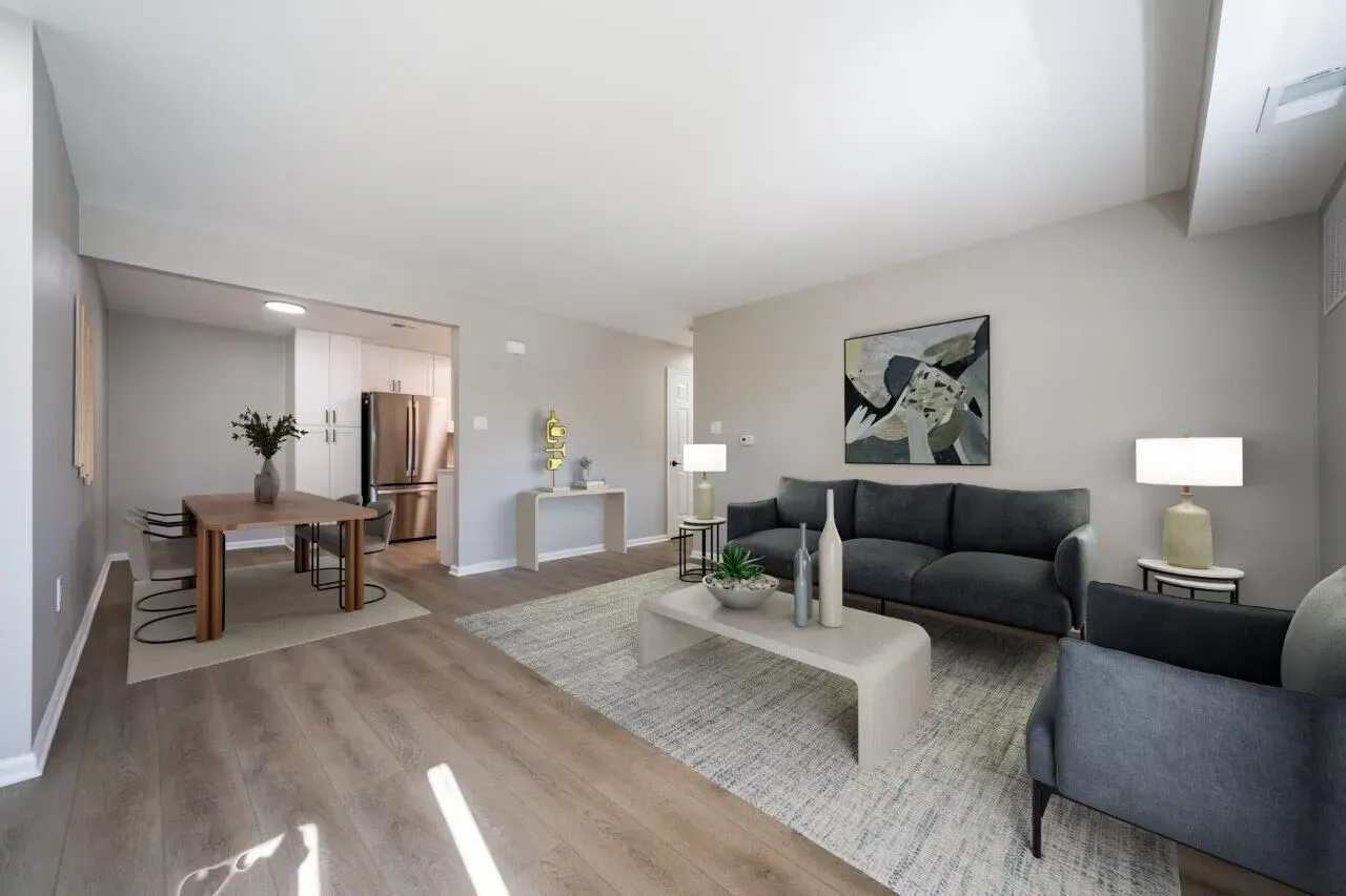Open-concept living room in a modern apartment with gray sofa, coffee table, and dining area. Visit us at Fox Ridge Apartments and view our modern, garden-style 1 and 2 bedroom apartments in Limerick, PA.