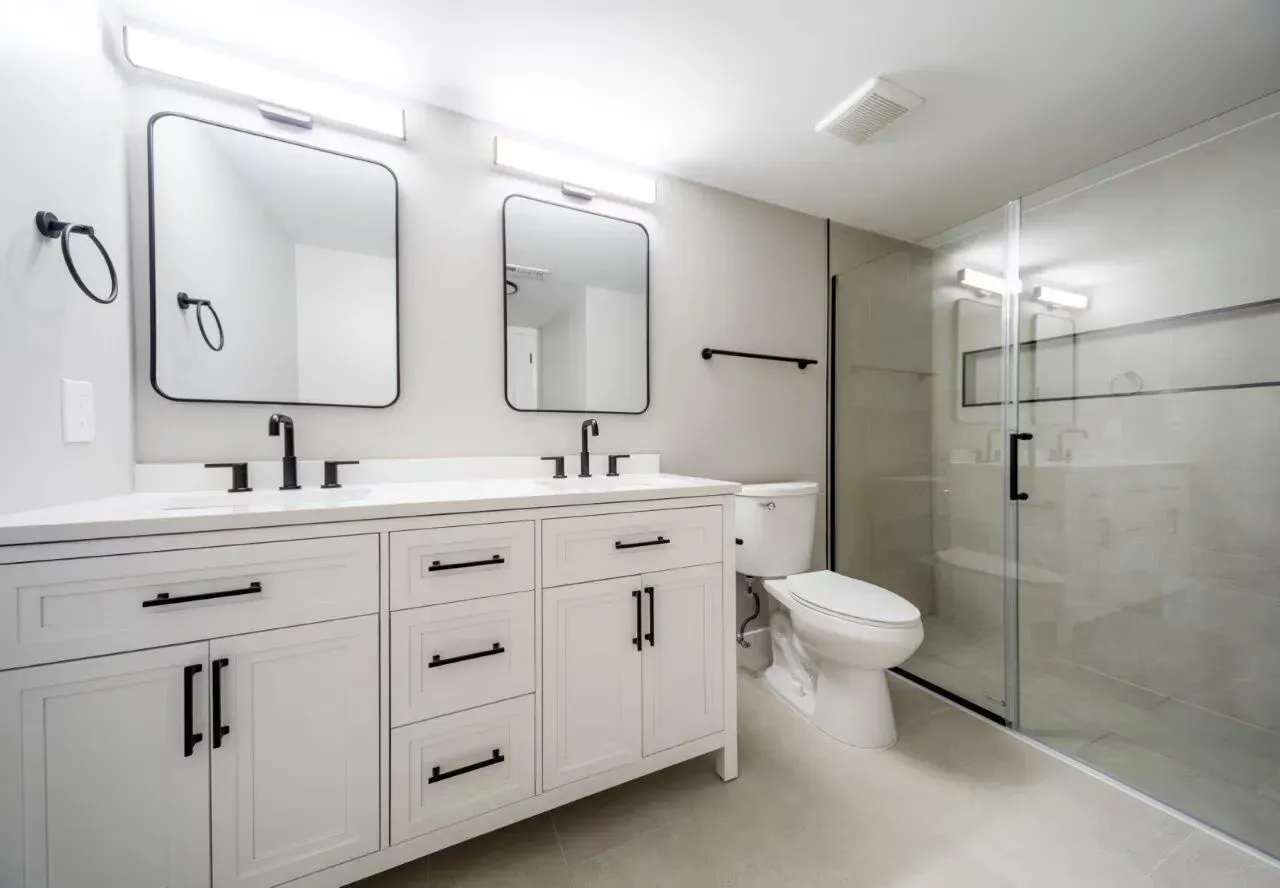 Modern bathroom with a double vanity, two mirrors, and a glass-enclosed shower. Visit us at Fox Ridge Apartments and view our modern, garden-style 1 and 2 bedroom apartments in Limerick, PA.