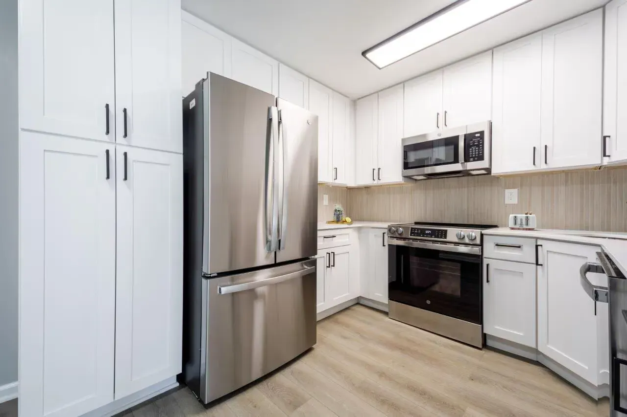 Modern white kitchen with stainless steel refrigerator, oven, microwave, and cabinetry. Visit us at Fox Ridge Apartments and view our apartments for rent in Limerick, PA.