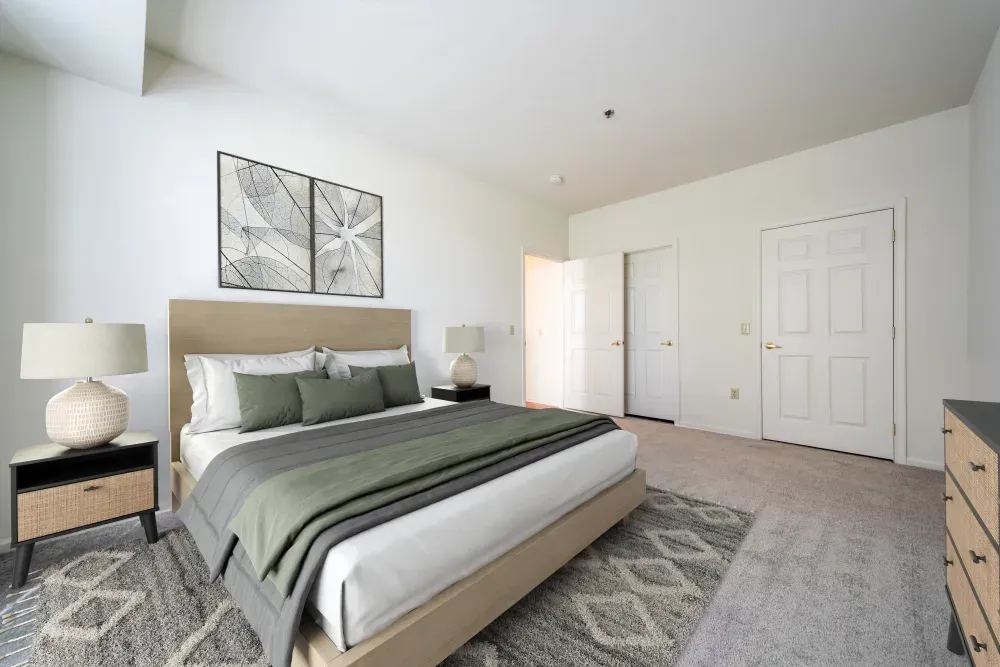 Modern bedroom in an apartment with a large bed, two nightstands, and neutral decor. Visit us at Fox Ridge Apartments and view our modern, garden-style 1 and 2 bedroom apartments in Limerick, PA.