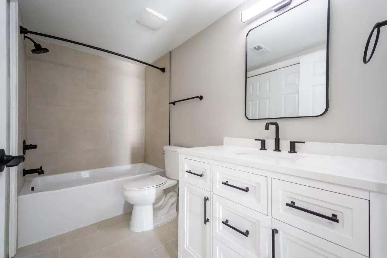 White bathroom with vanity, black fixtures, and a tub/shower combo. Visit us at Fox Ridge Apartments and view our modern, garden-style 1 and 2 bedroom apartments in Limerick, PA.