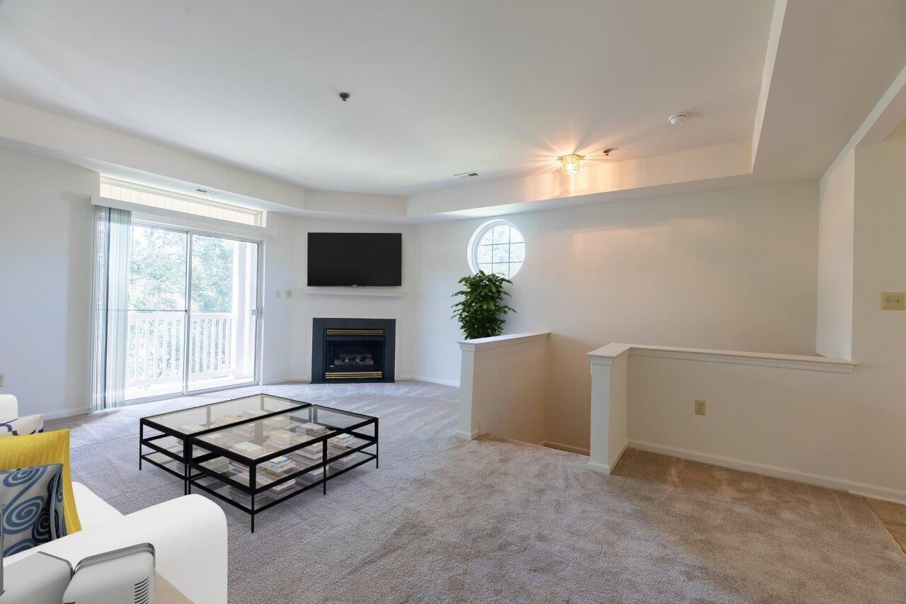 Bright living room with a fireplace, wall-mounted TV, and balcony door. Visit us at Fox Ridge Apartments and view our pet-friendly apartments for rent in Limerick, PA.