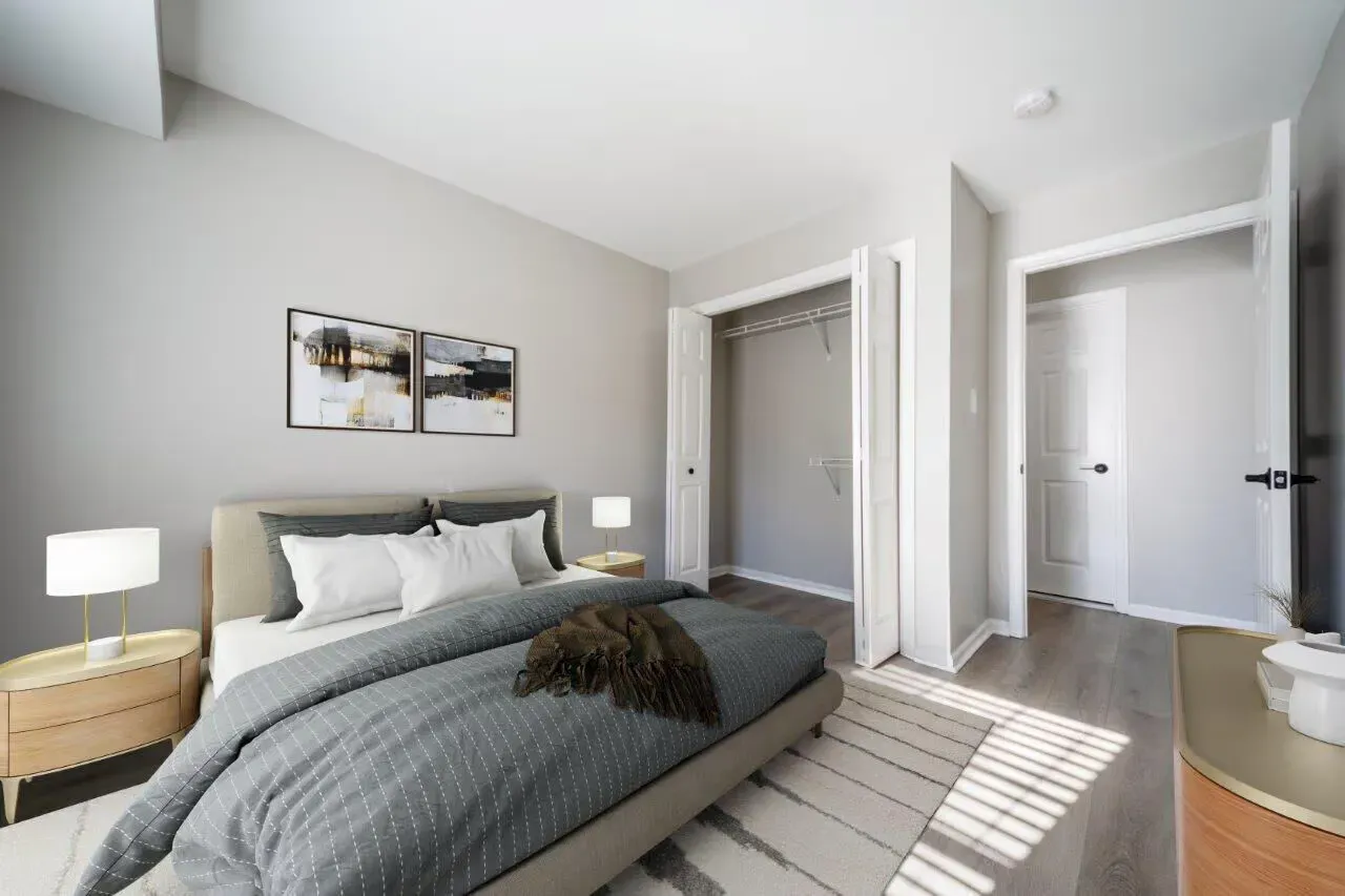 Modern apartment bedroom with a large bed, two nightstands, and an open closet. Visit us at Fox Ridge Apartments and view our modern, garden-style 1 and 2 bedroom apartments in Limerick, PA.