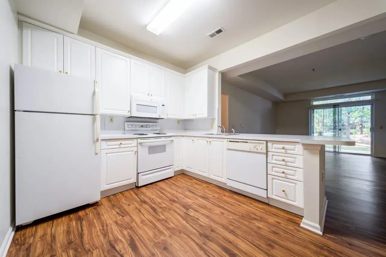 White kitchen with refrigerator, stove, microwave, dishwasher, and wood-look flooring. Visit us at Fox Ridge Apartments and view our apartments for rent in Limerick, PA.