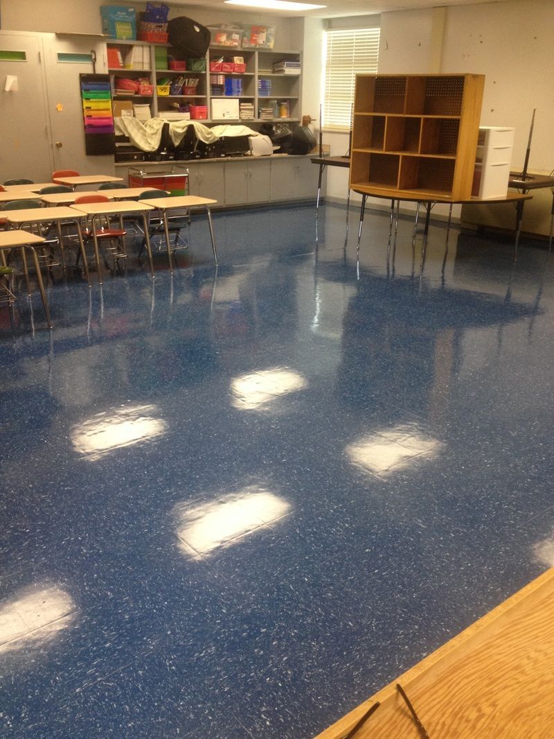 A classroom with blue floors and tables and chairs