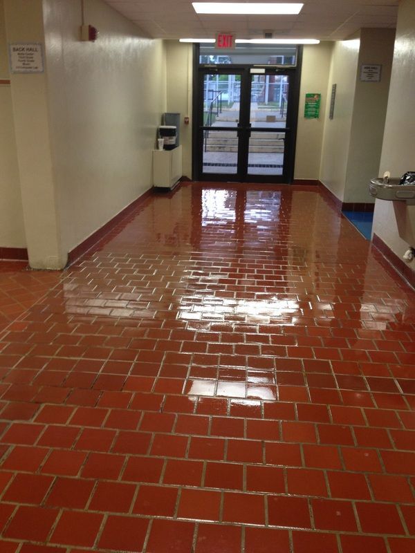 A hallway with red tiles and a water fountain
