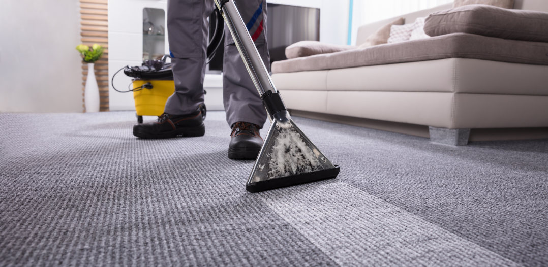 A man is cleaning a carpet with a vacuum cleaner in a living room.