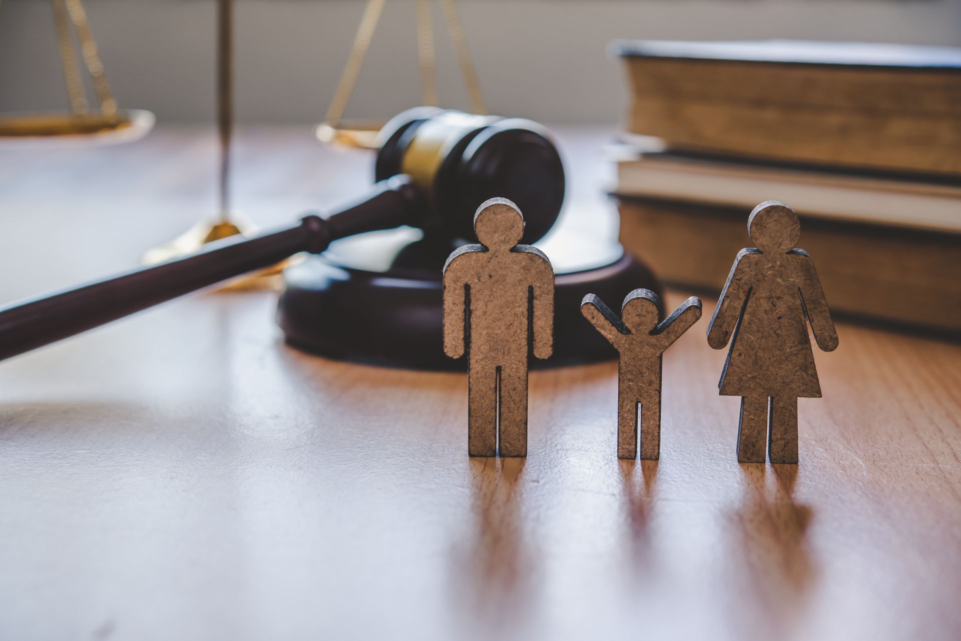Paper family figures in front of a judge’s gavel and law books, symbolizing family law.