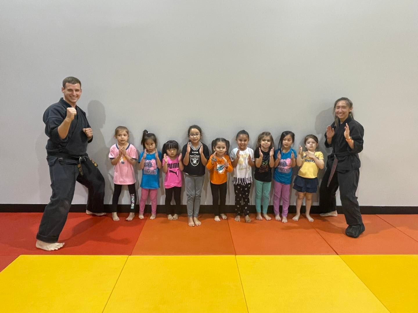 A group of children are standing next to each other on a yellow mat in a gym.