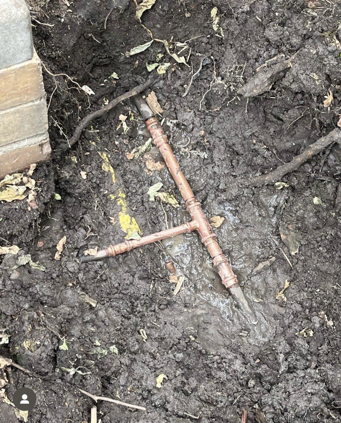 Image depicts a mudded area near the corner of a house with an exposed copper T junction pipe that has been repaired and is the post image of the burst pipe on the left side of the page.