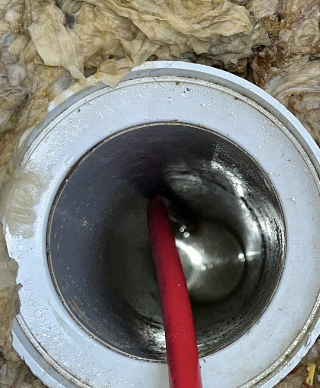 Image depicts CCTV technology being used down what was a blocked sewer PVC pipe. The camera is attached to a long red cable rigid enough to push down through a blockage.