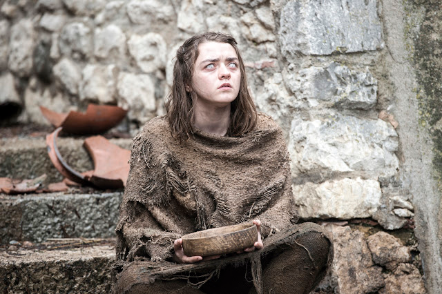 Arya Stark in rags, looking up, holding a wooden bowl, sitting on stone steps, grey and brown tones.