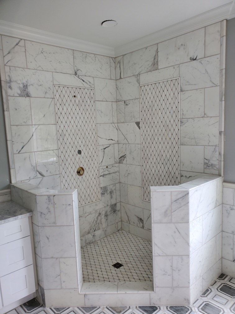 A bathroom with marble tiles and a walk in shower.