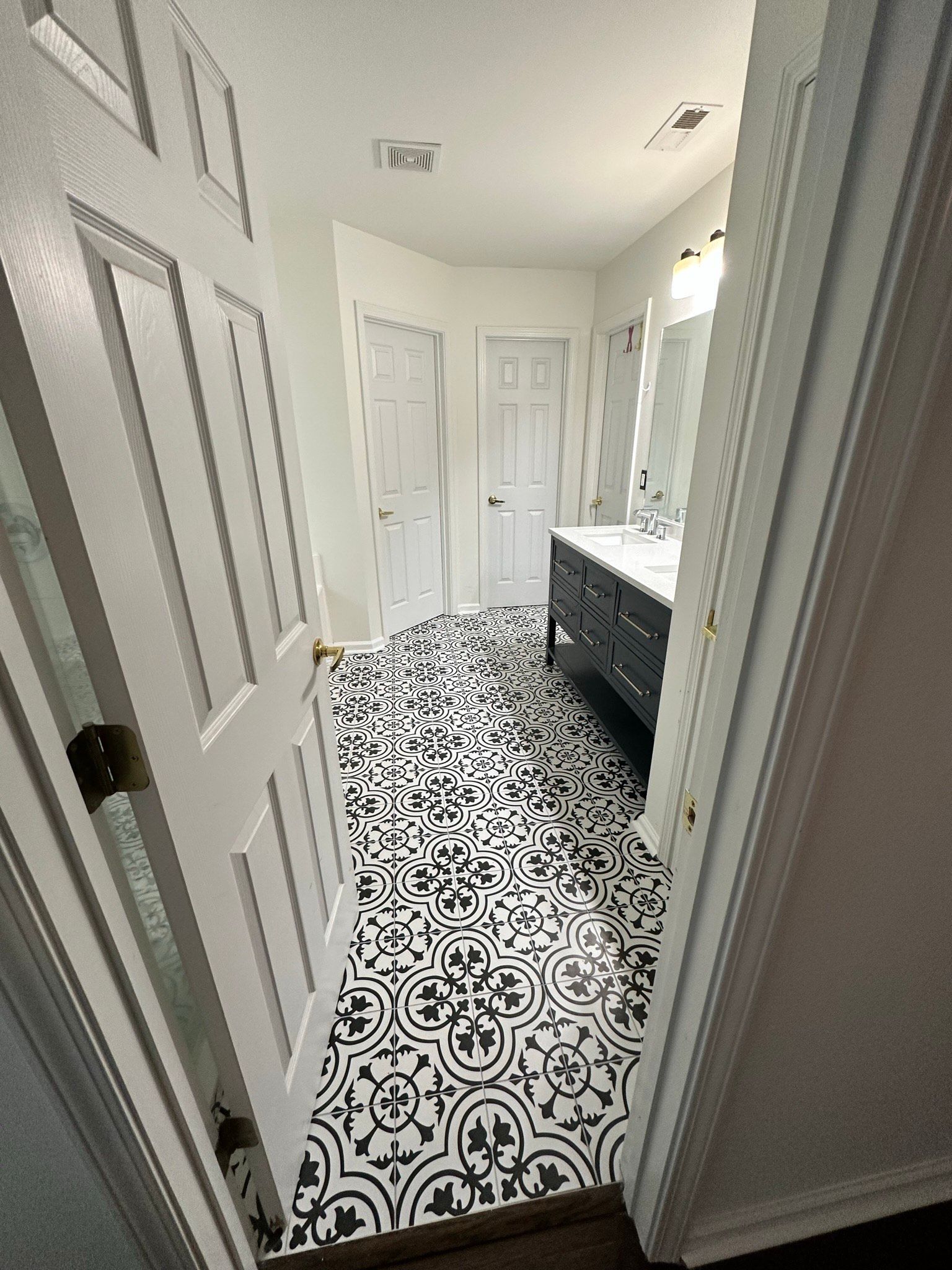 A bathroom with a black and white tile floor and a sink.