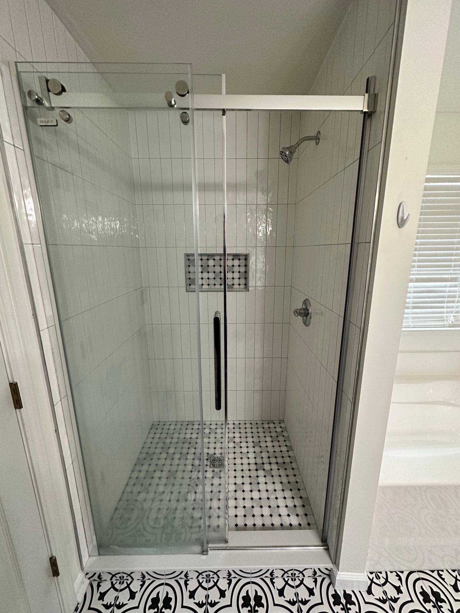 A bathroom with a walk in shower with a sliding glass door.