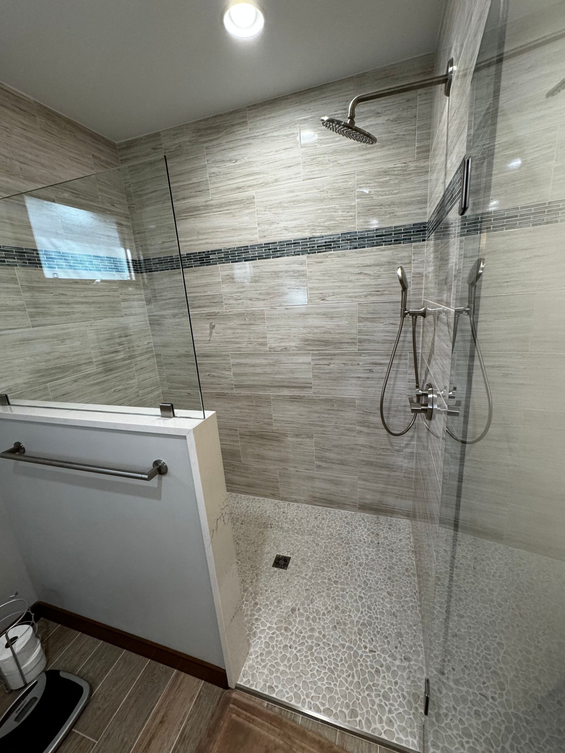A bathroom with a walk in shower with a glass door.