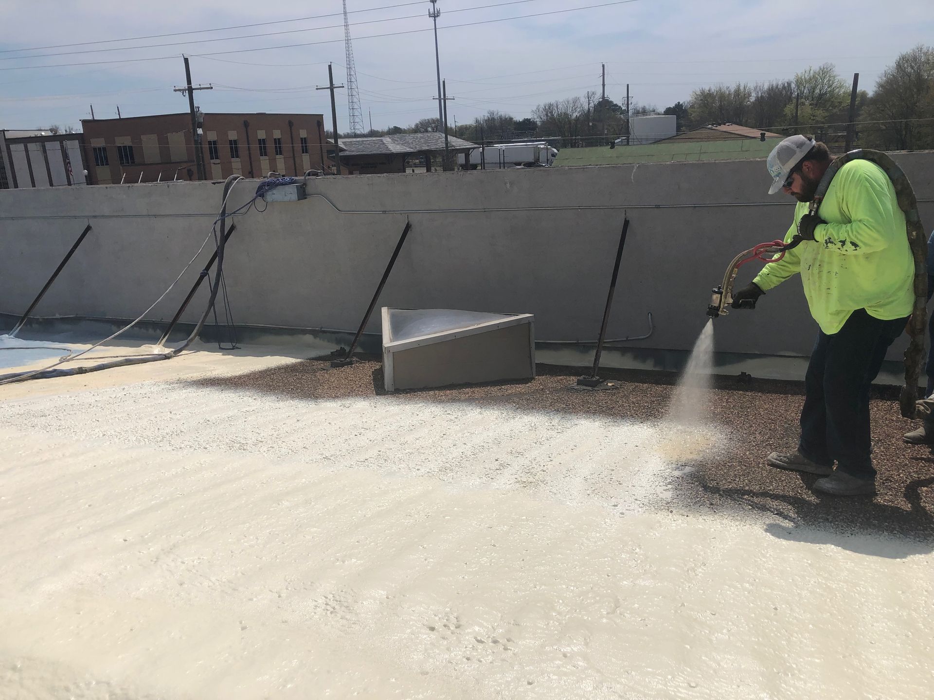 A man is spraying foam on a roof.