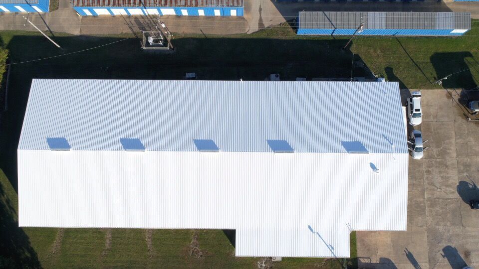 An aerial view of a large white building with a white roof.