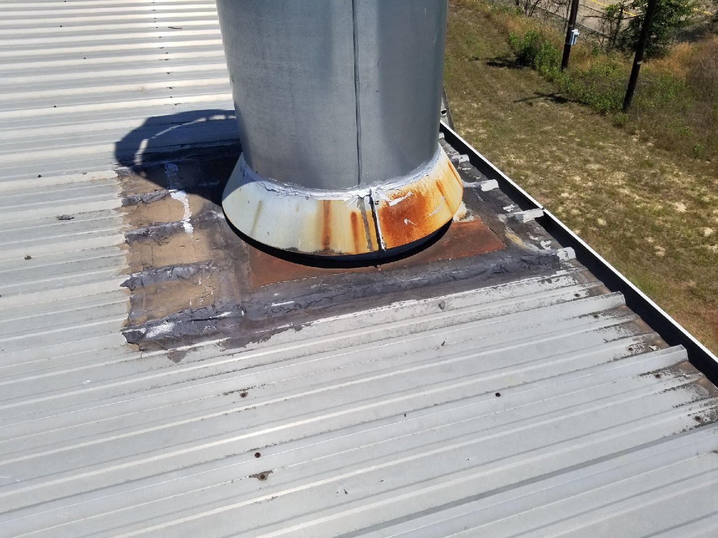 A rusty chimney is sitting on top of a metal roof.
