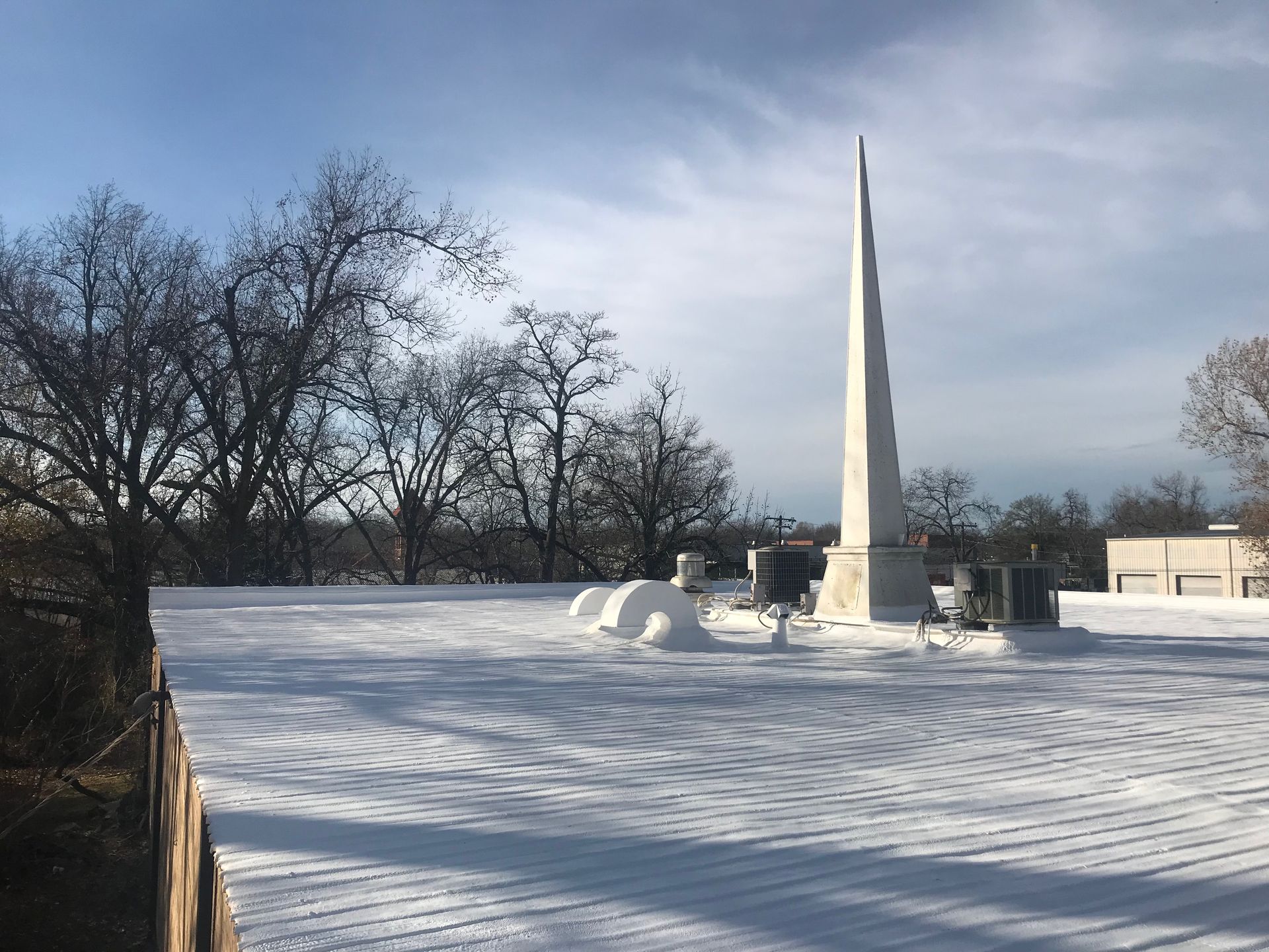 There is a large obelisk in the middle of a snowy field.