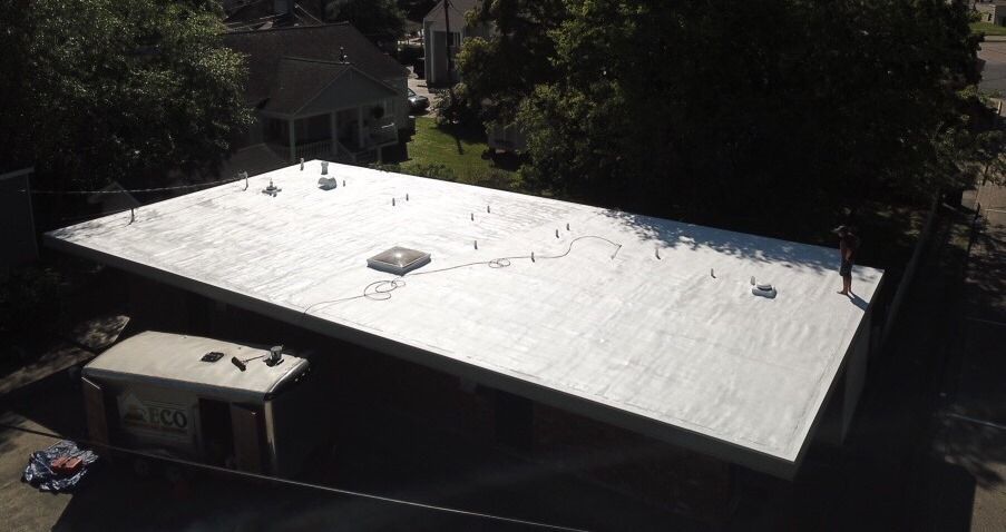 An aerial view of a white roof with trees in the background