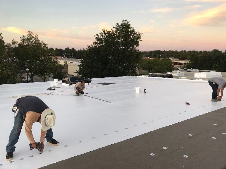Two men are working on a white roof.