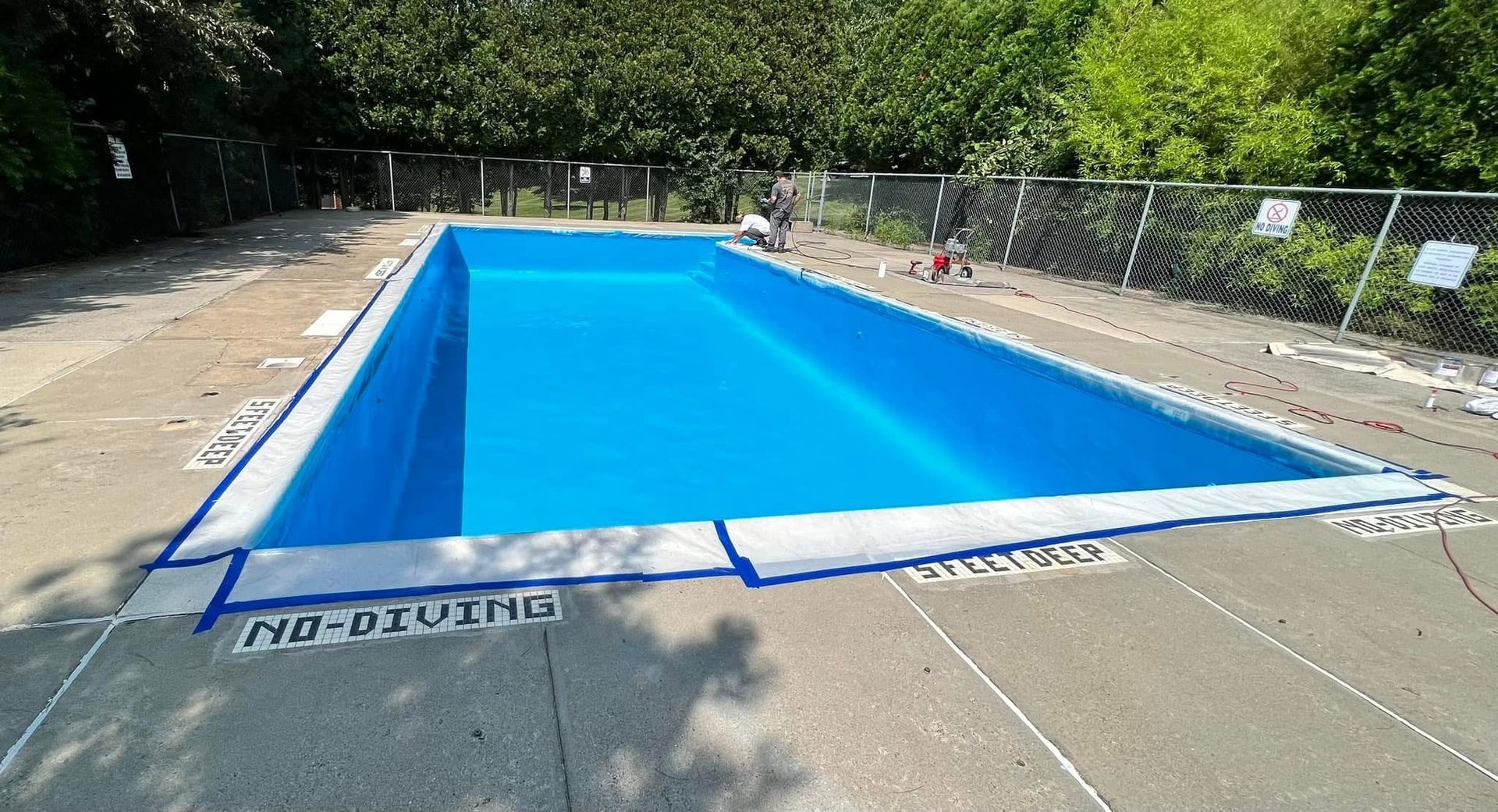 A large blue swimming pool with a fence around it