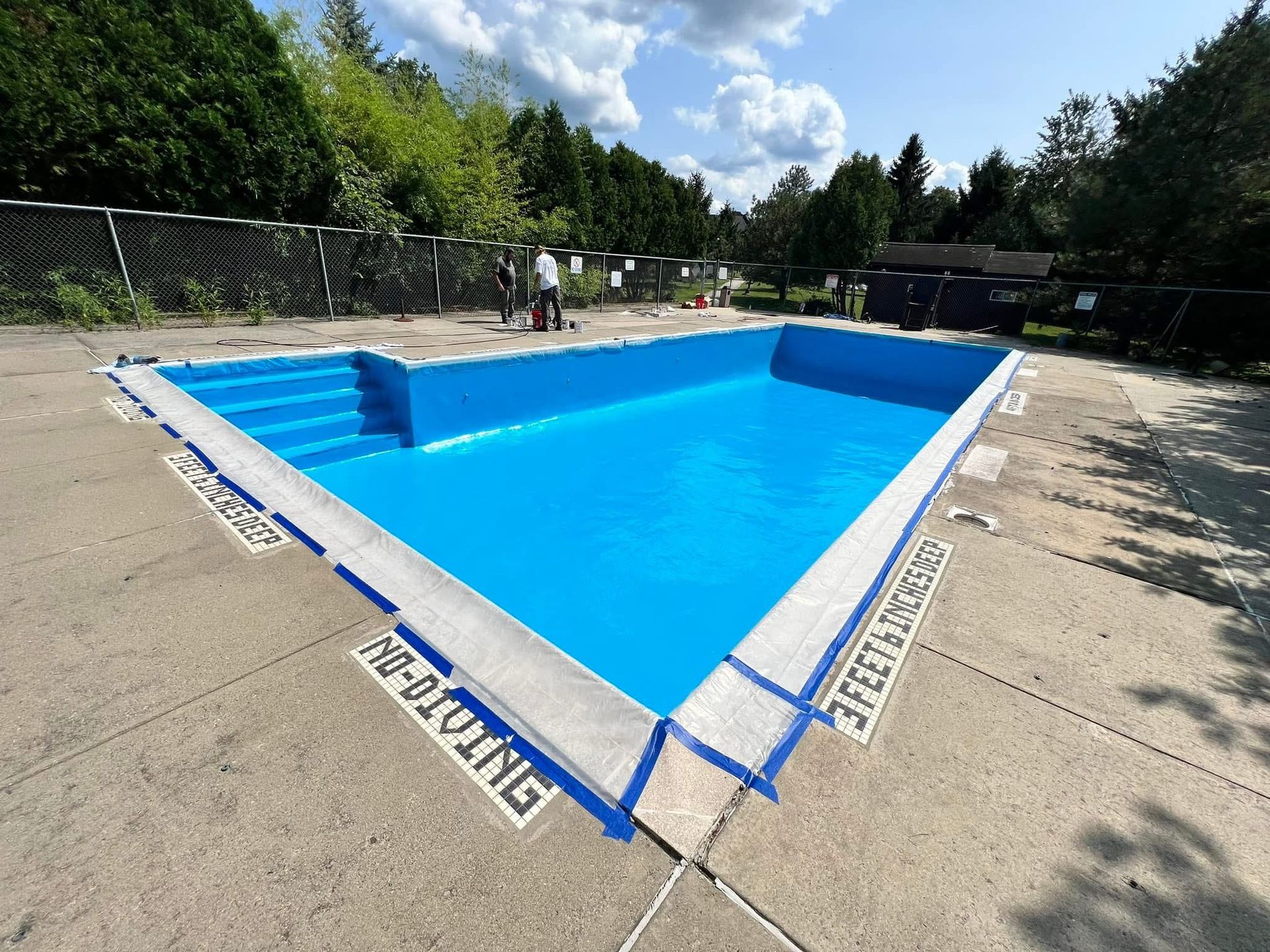 A large blue swimming pool with the words no diving painted on the side