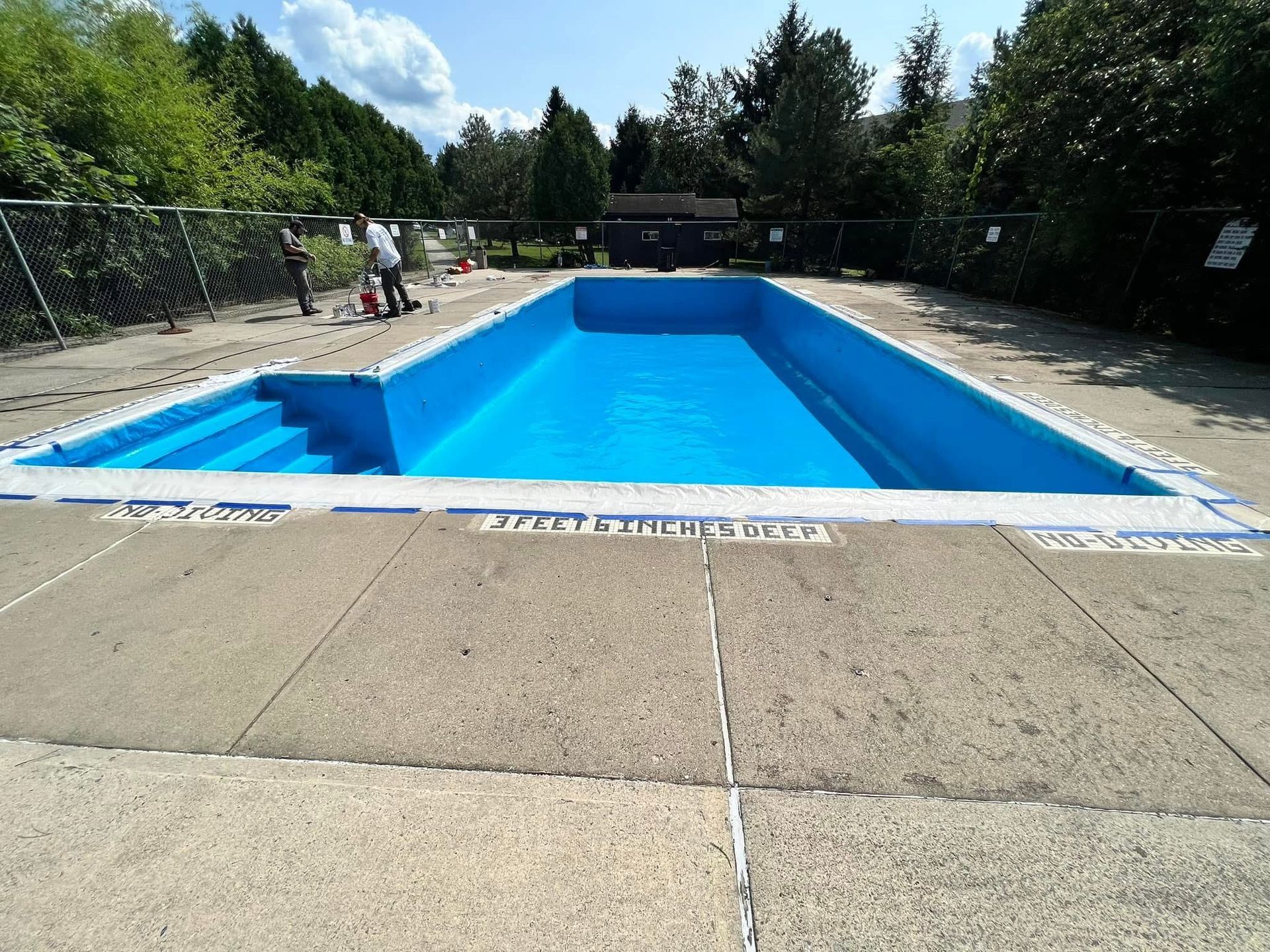 A large blue swimming pool with a fence around it