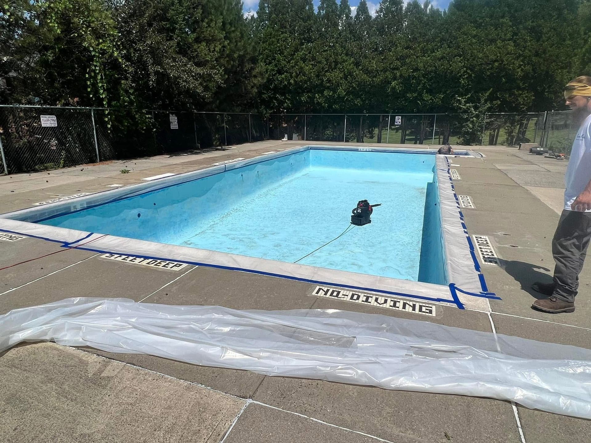 A man is standing next to an empty swimming pool