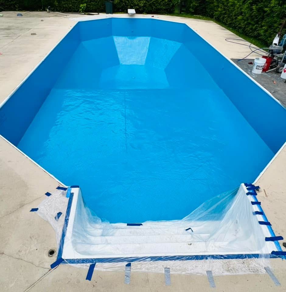 A large swimming pool with blue water is being painted