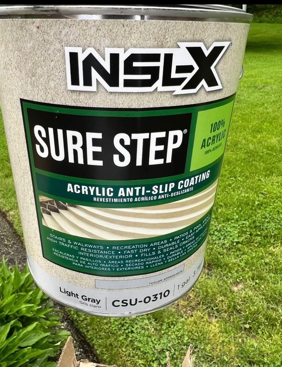 A bucket of inslx sure step acrylic anti slip coating is sitting on a sidewalk.