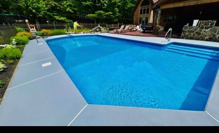 A large swimming pool is surrounded by chairs and a house.